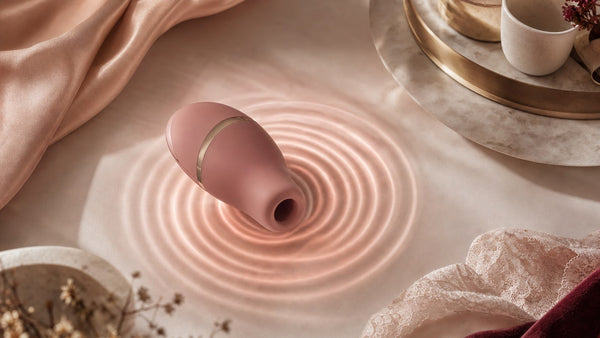 Onde concentriche di luce rosa su raso intorno a un piccolo dispositivo arrotondato
