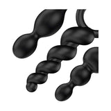 Dettaglio ravvicinato di tre plug anali neri in silicone morbido Satisfyer, forme a doppia sfera e spirale con anelli di ritenuta
