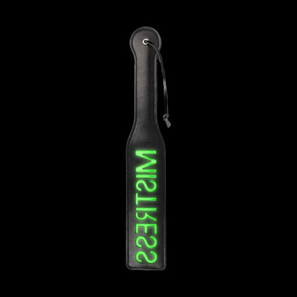 Paddle glow in the dark nero con scritta MISTRESS verde neon su sfondo scuro