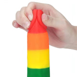 Primo piano testa rossa dildo silicone arcobaleno premuta per dimostrare morbidezza