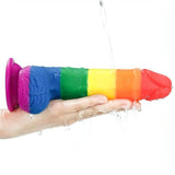 Dildo arcobaleno impermeabile in silicone lavato sotto l'acqua su sfondo bianco