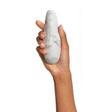 Mano che tiene stimolatore clitoride Womanizer bianco marmo texture dettagliata