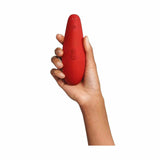 Mano che tiene Womanizer rosso ergonomia e pulsanti incisi superficie morbida